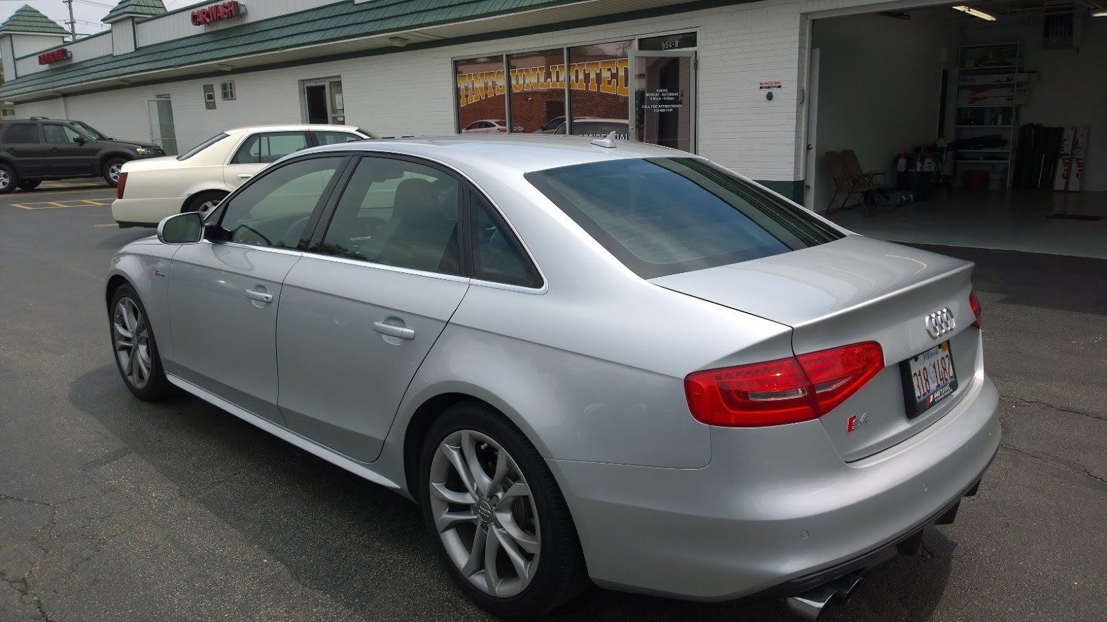 A silver audi a4 is parked in front of a building