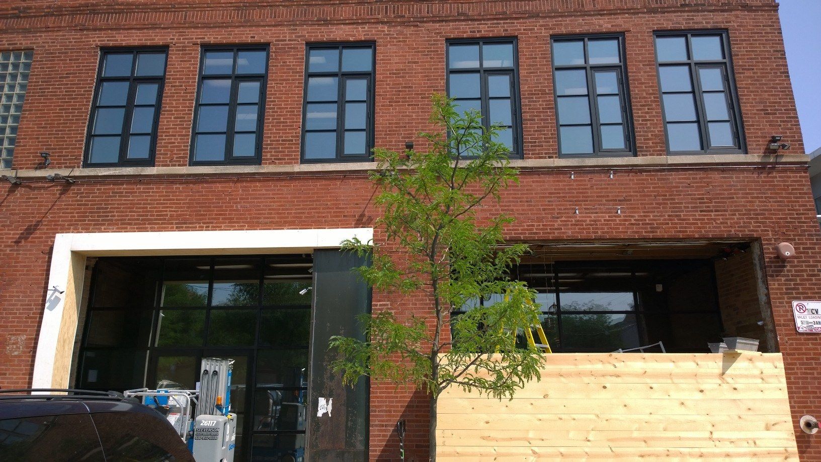 A brick building with a lot of windows and a tree in front of it.