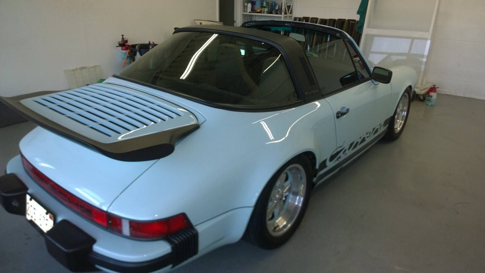 A white porsche targa is parked in a garage