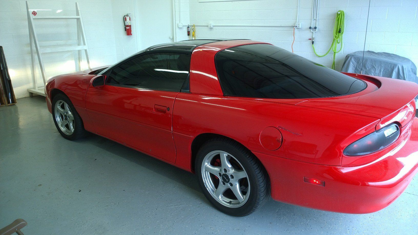 A red car with black windows is parked in a garage.