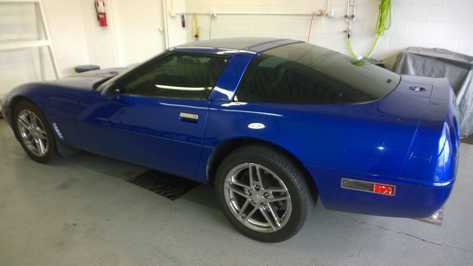 A blue corvette is parked in a garage