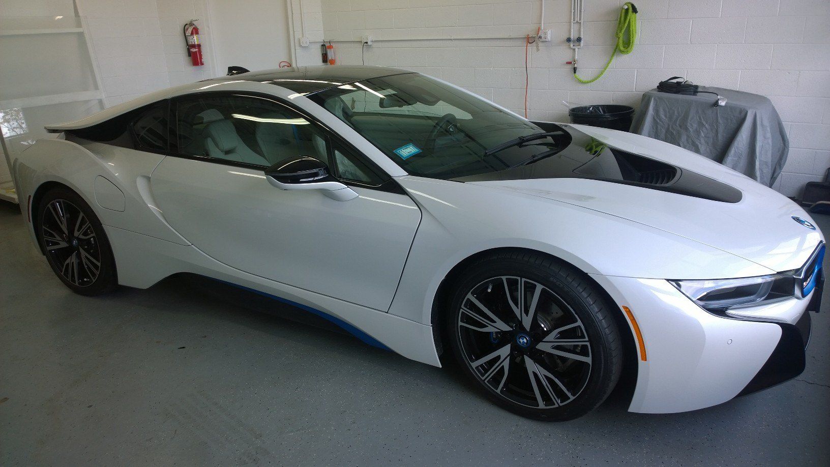 A white bmw i8 is parked in a garage.
