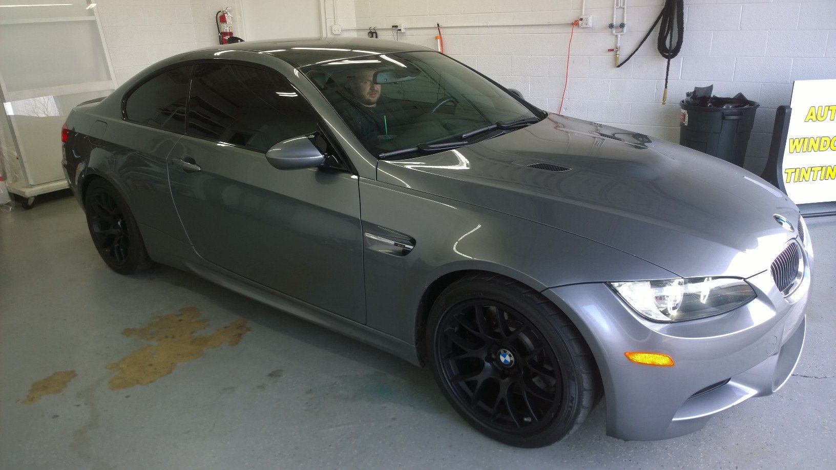 A gray bmw m3 is parked in a garage.