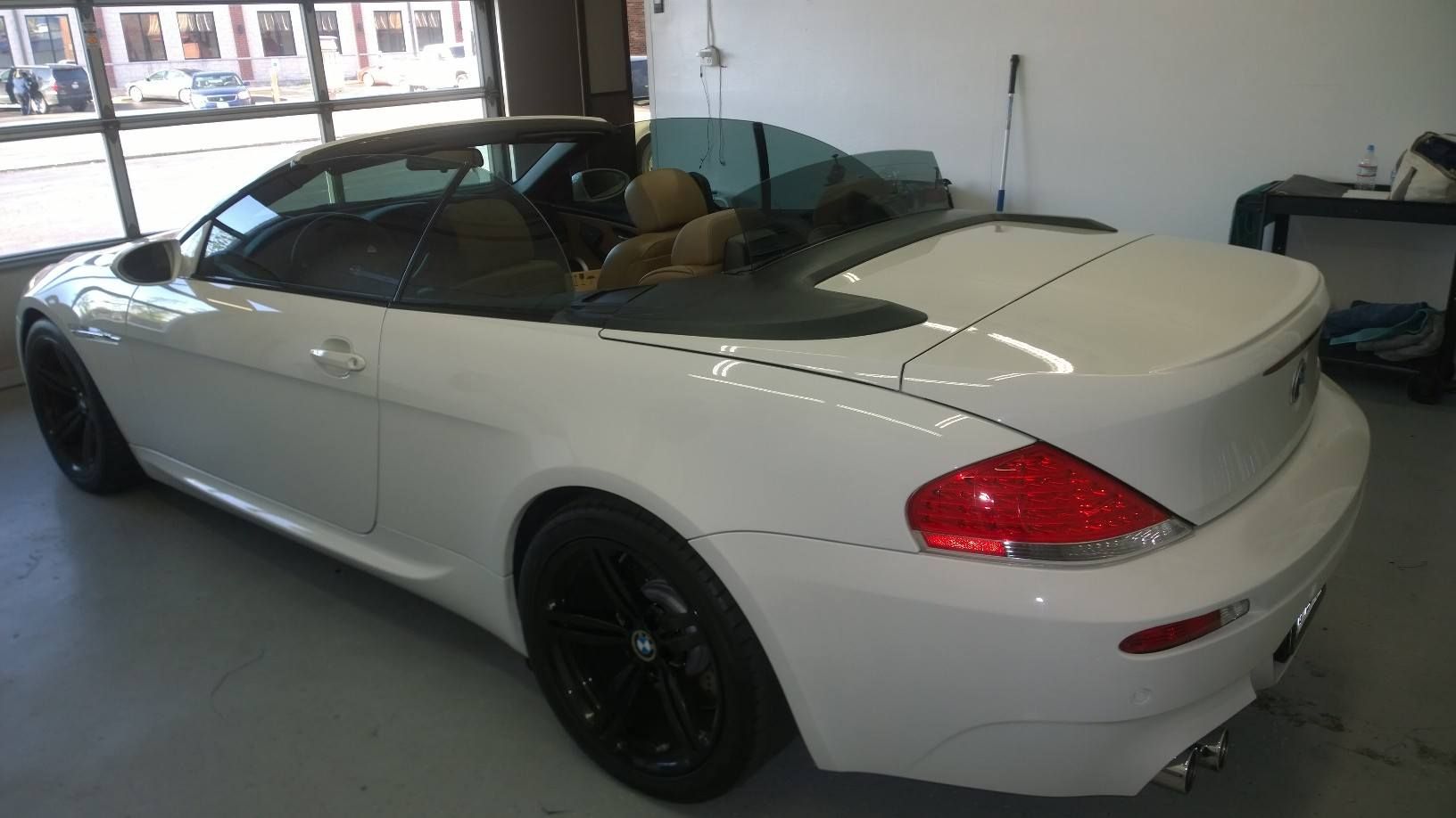 A white convertible car is parked in a garage.