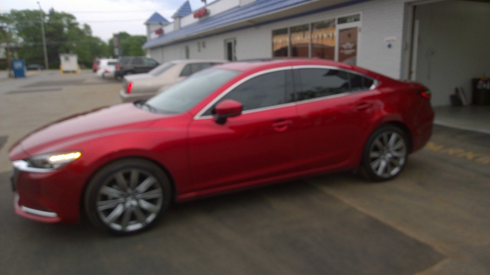 A red car is parked in front of a building