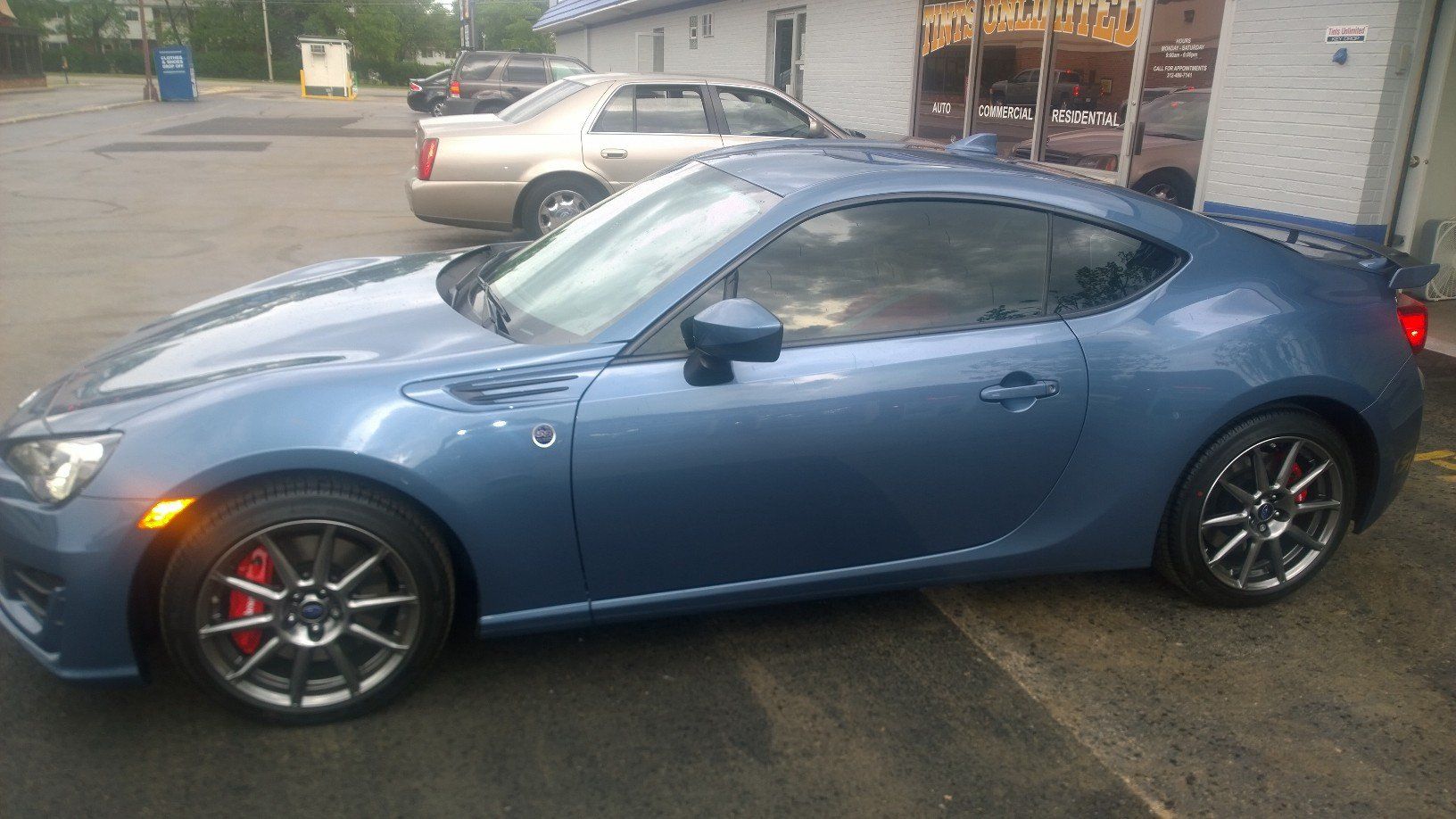 A blue sports car is parked in a parking lot.