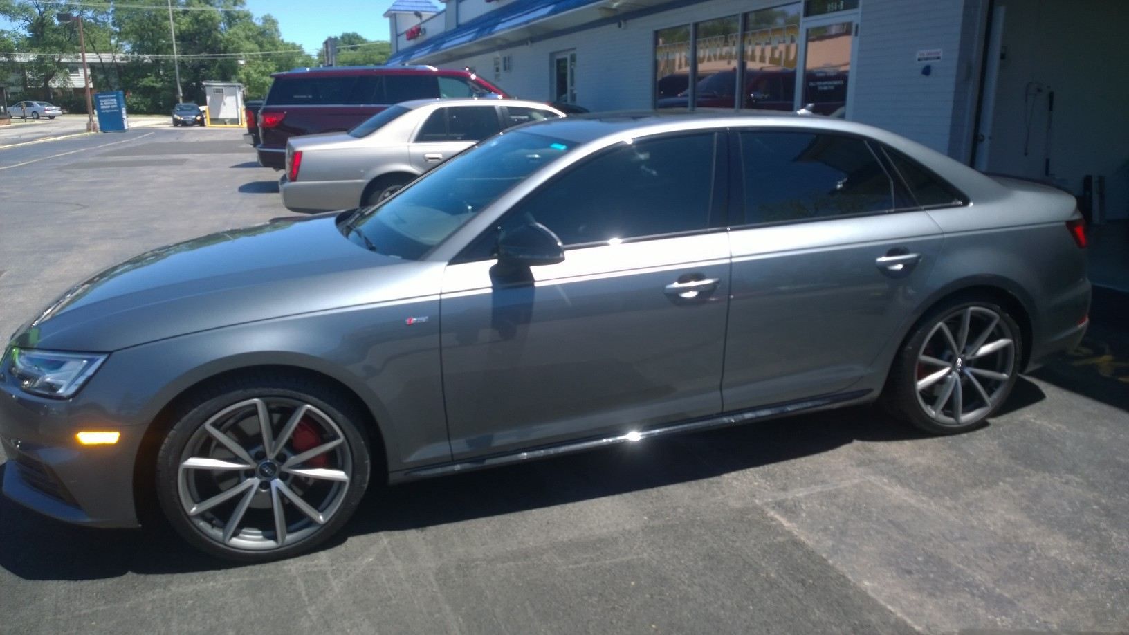 A gray car is parked in a parking lot in front of a building