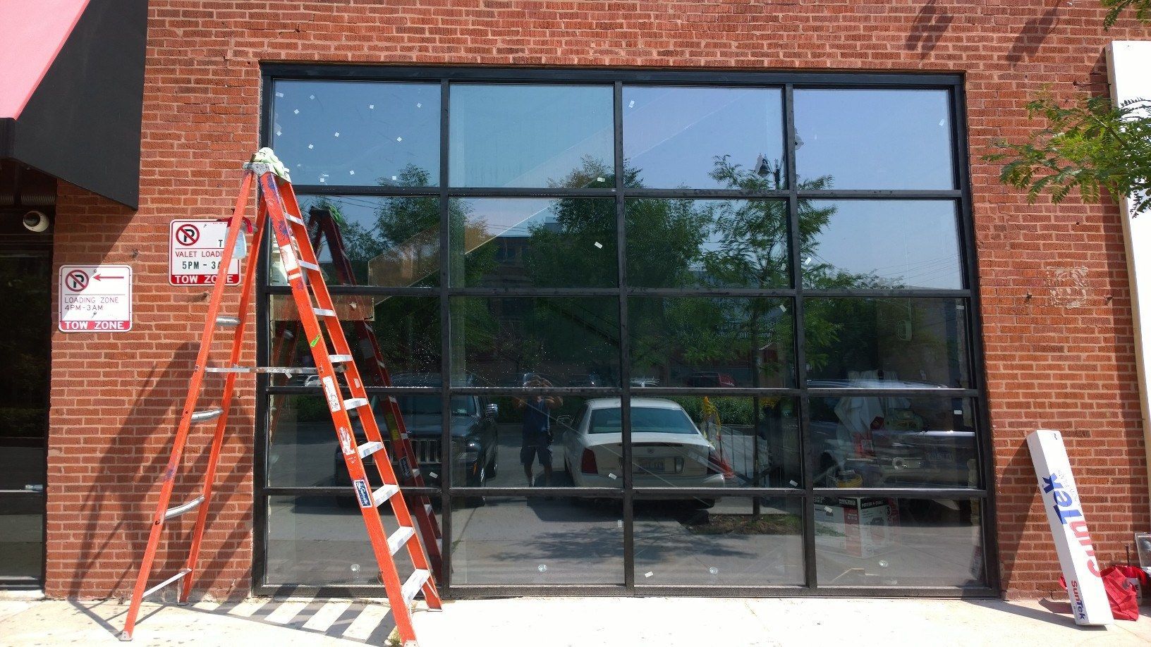 A ladder is sitting on the sidewalk in front of a brick building.