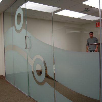 A man standing in front of a glass door with a red exit sign