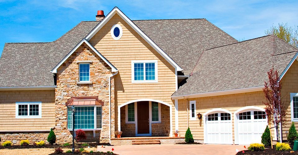 A large house with a gray roof and white garage doors