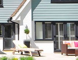 A house with a patio with chairs and a couch in front of it.