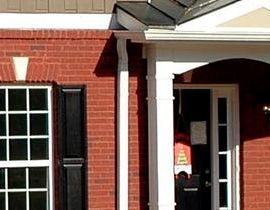 A red brick house with a white porch and black shutters