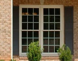 A brick house with a white window and black shutters.