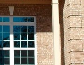 A brick building with a white window and a white pillar.