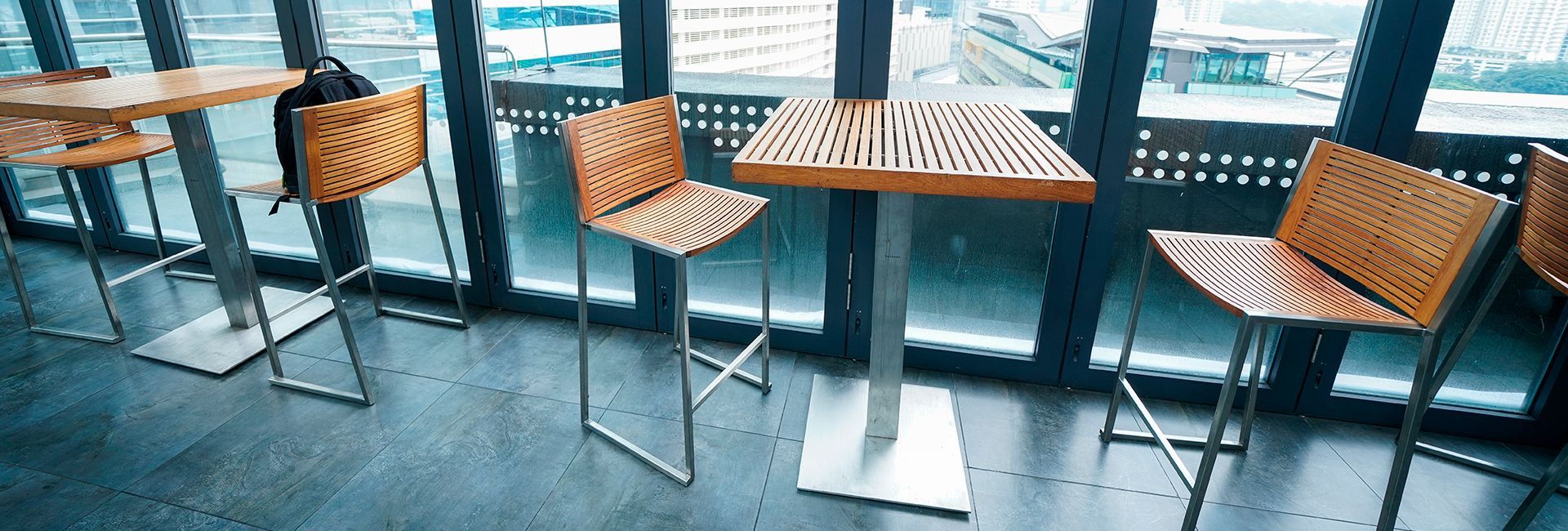 A row of tables and chairs in front of a window in a restaurant.