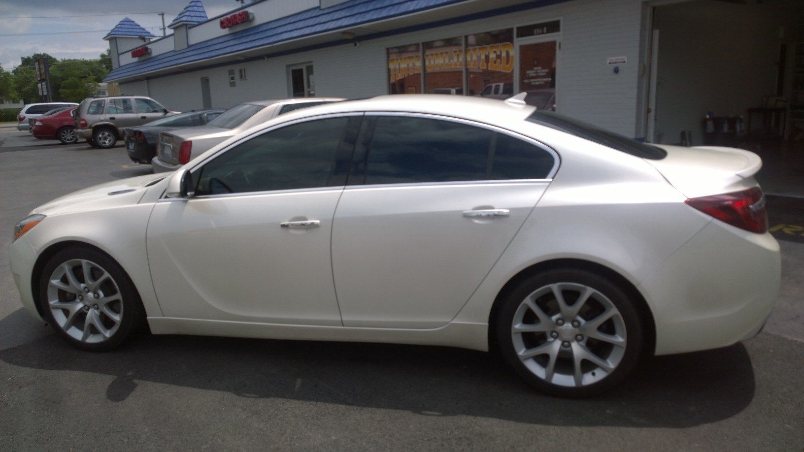 A white car is parked in front of a building