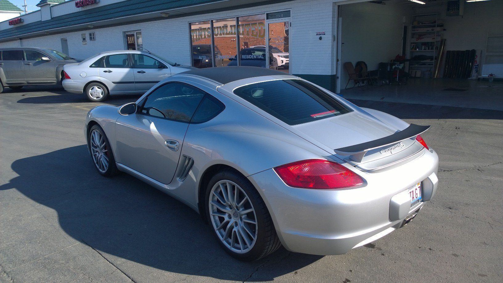 A silver sports car is parked in front of a building