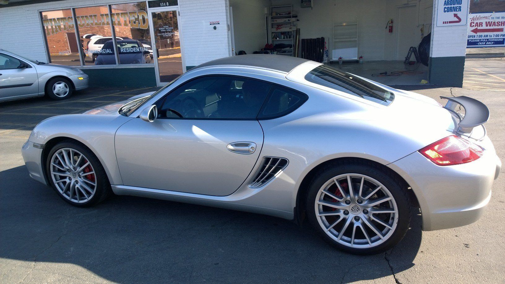 A silver sports car is parked in front of a car wash.