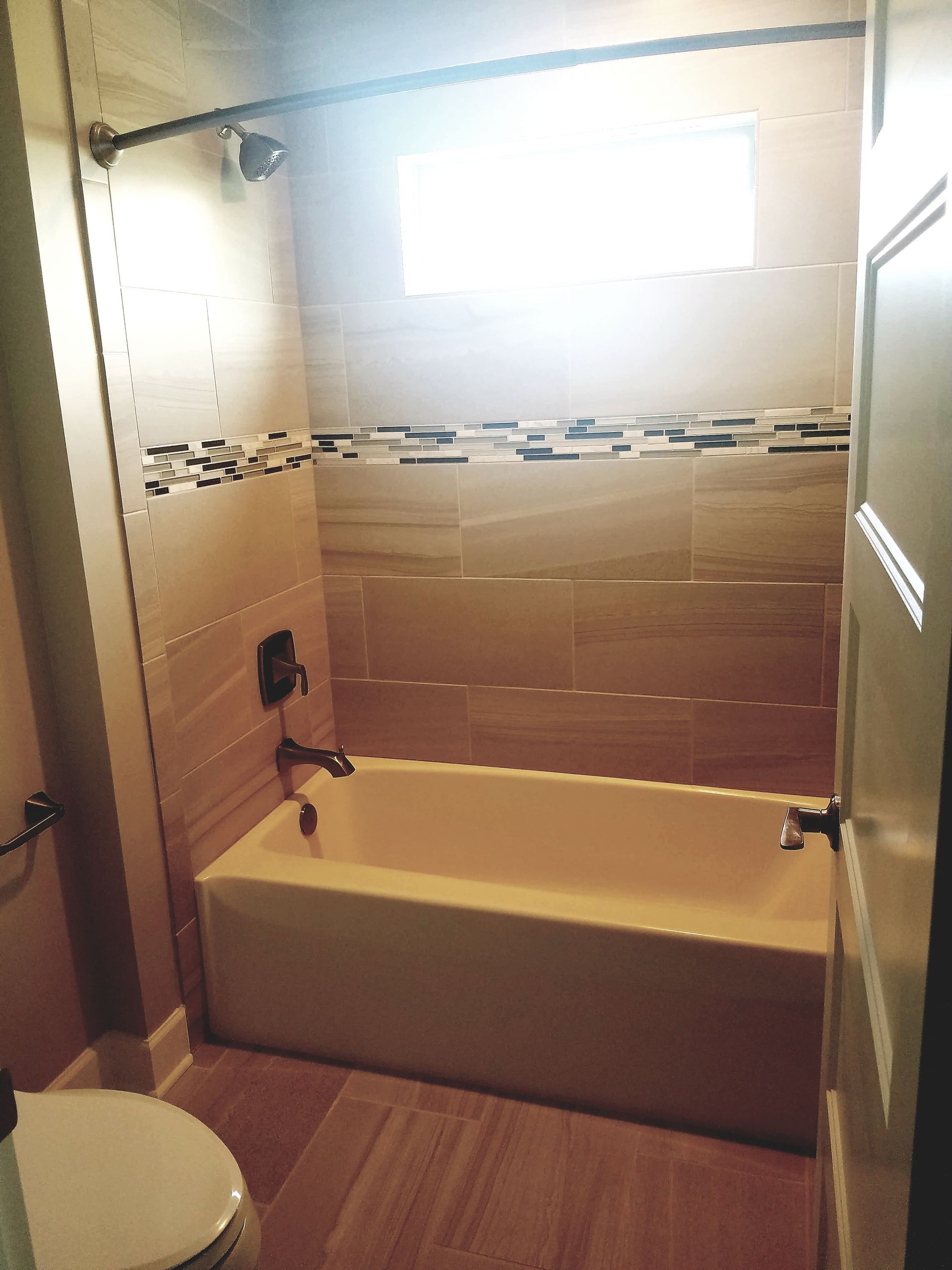 A bathroom with a tub , toilet and shower.