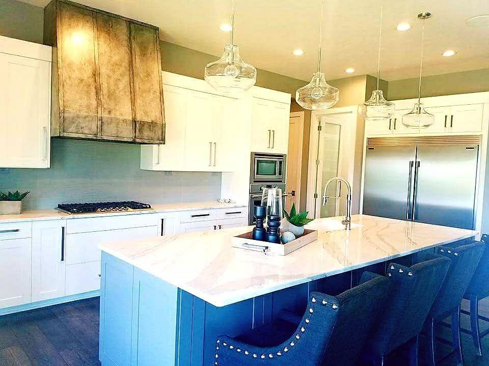 A kitchen with white cabinets and stainless steel appliances and a large island.