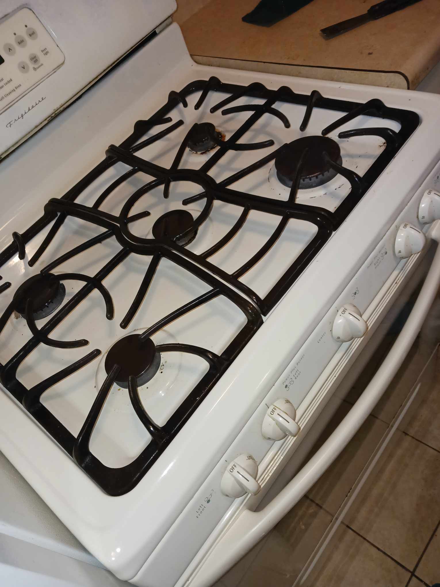 A white stove with black burners and knobs