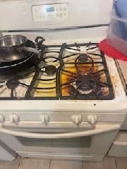 A dirty stove top oven with pots and pans on it.