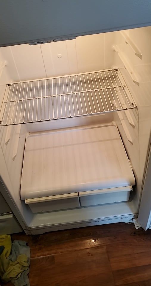 The inside of an empty refrigerator with a shelf and drawers.