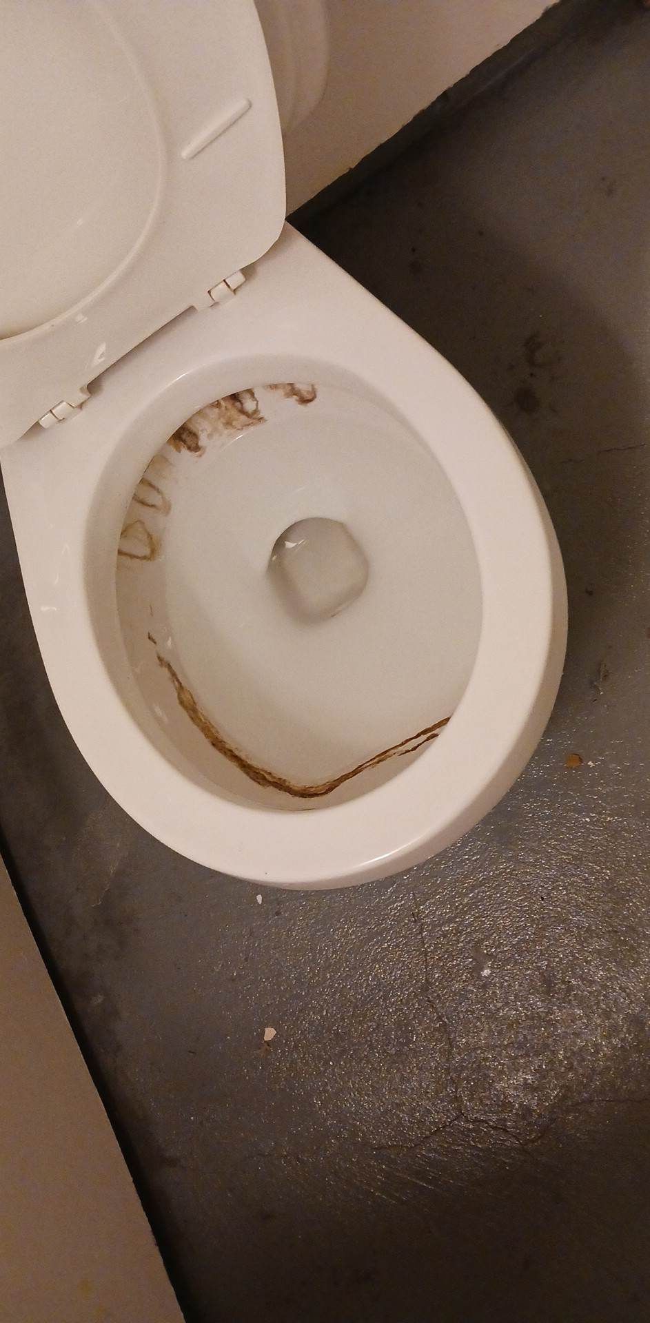 A close up of a dirty toilet on a bathroom floor.