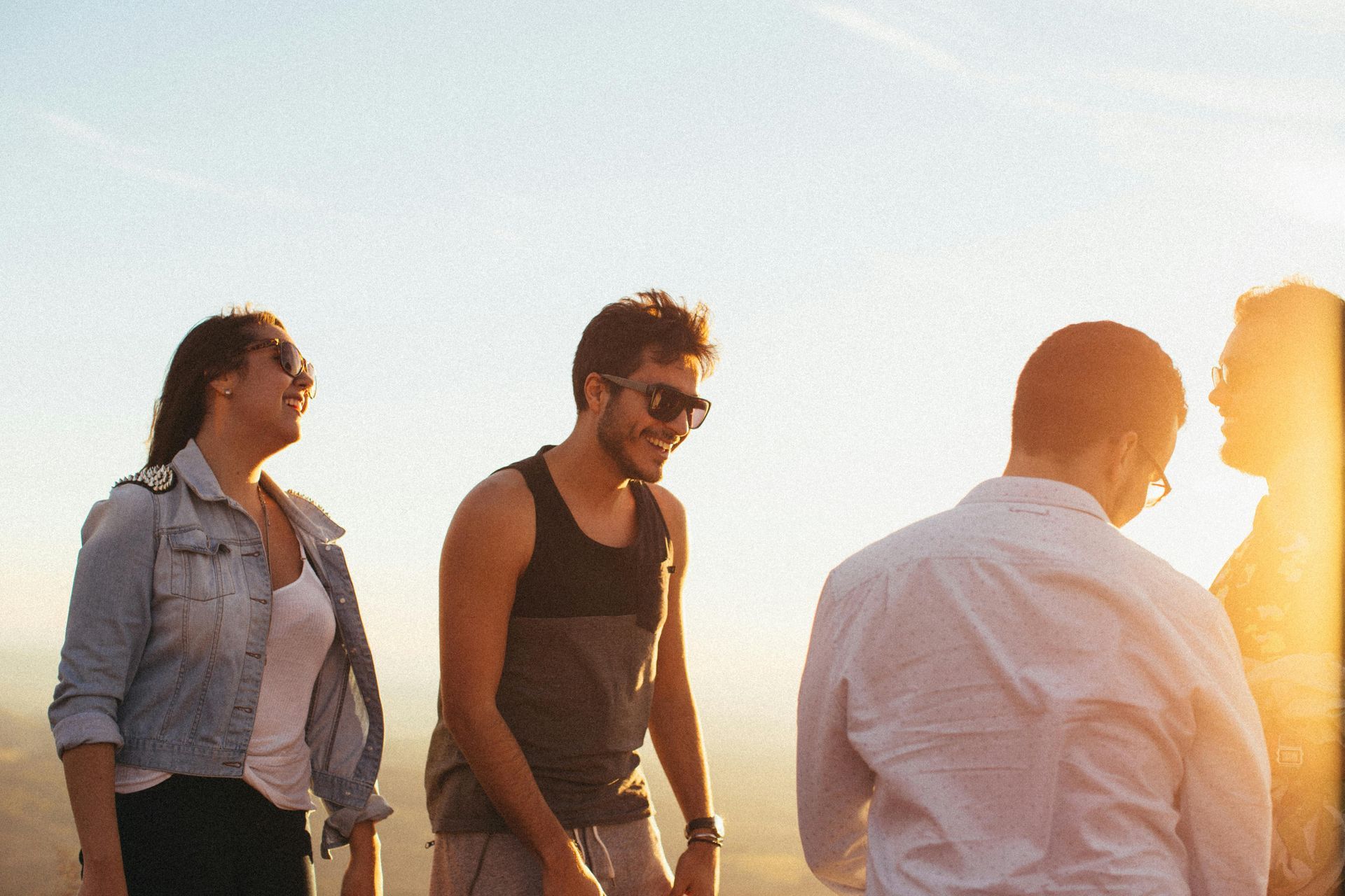 Group of friends laughing, enjoying a sunny day outdoors.