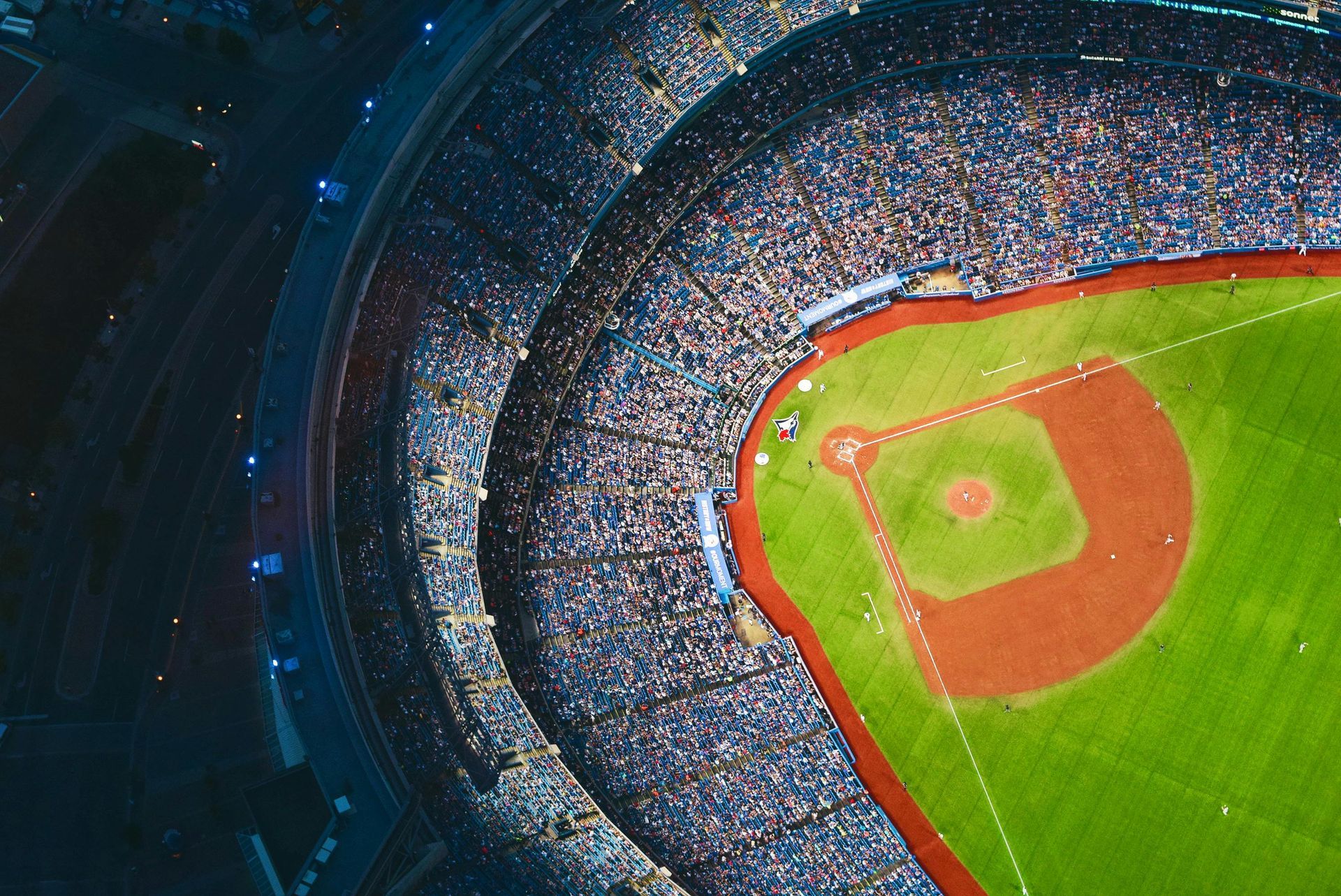 Aerial view of a baseball stadium filled with fans, focus on the diamond-shaped field and green grass.
