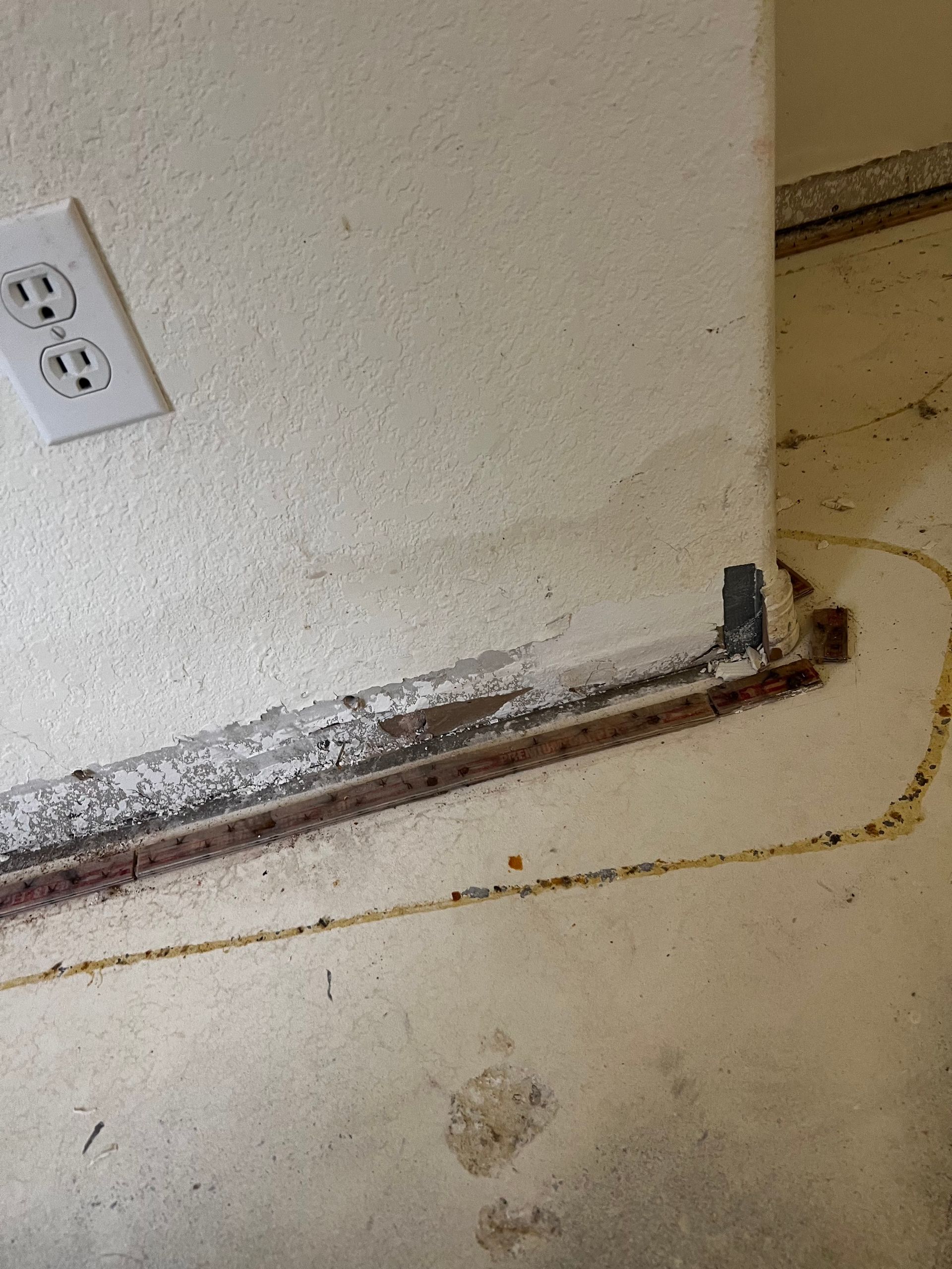 A white wall with a white electrical outlet on it