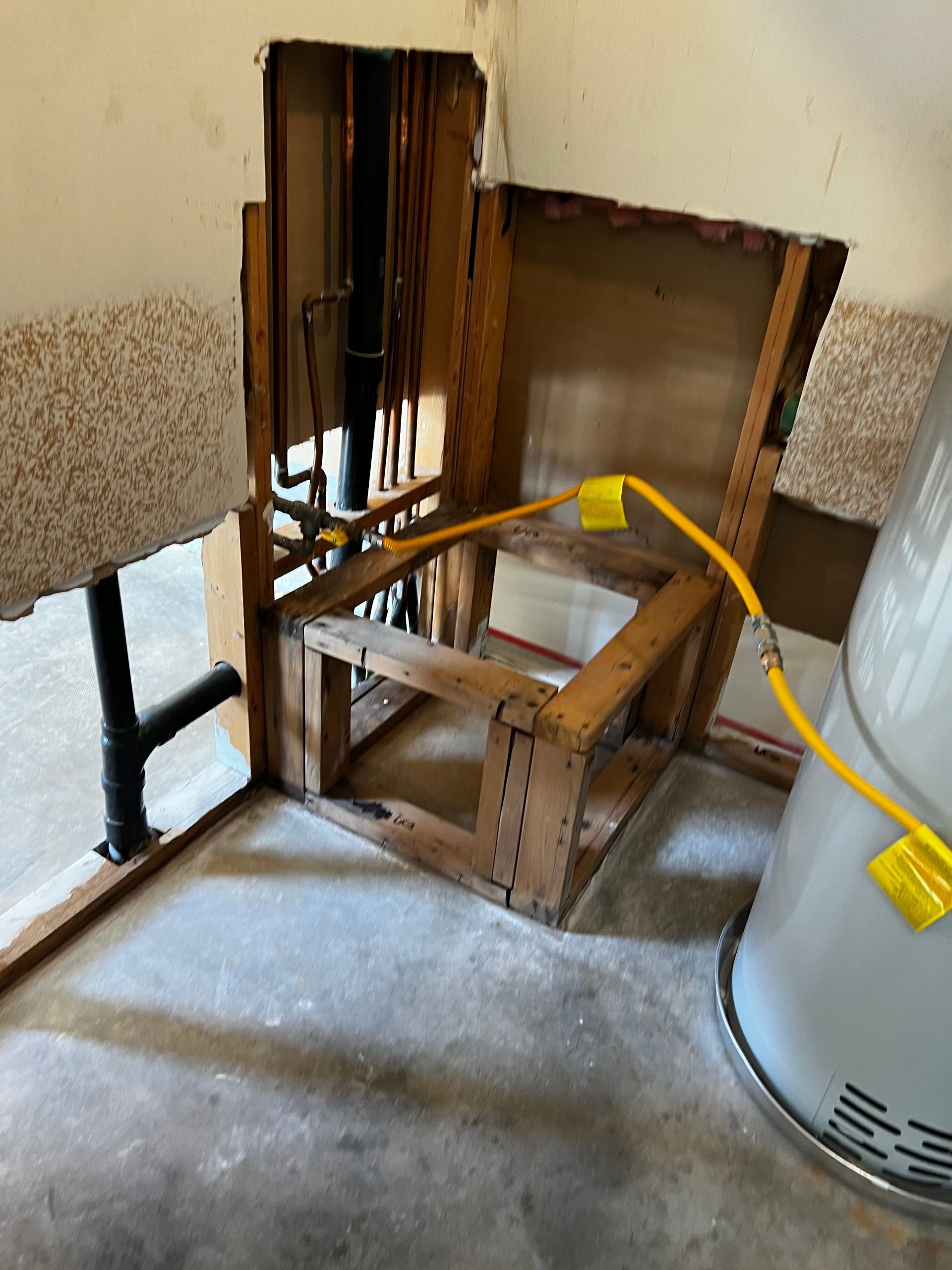 A water heater is being installed in a room with a hole in the wall.