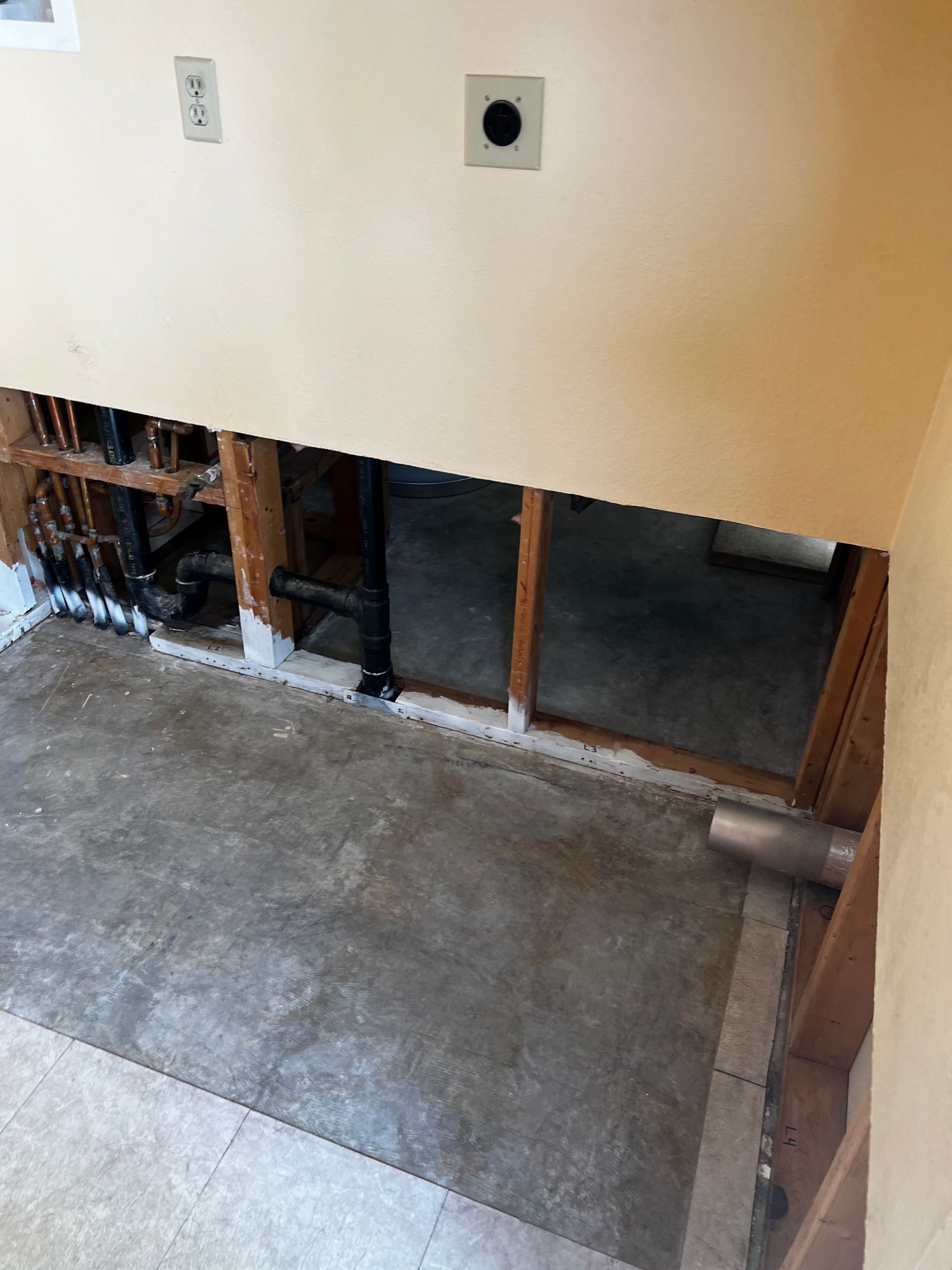 A room with a hole in the wall and a concrete floor.