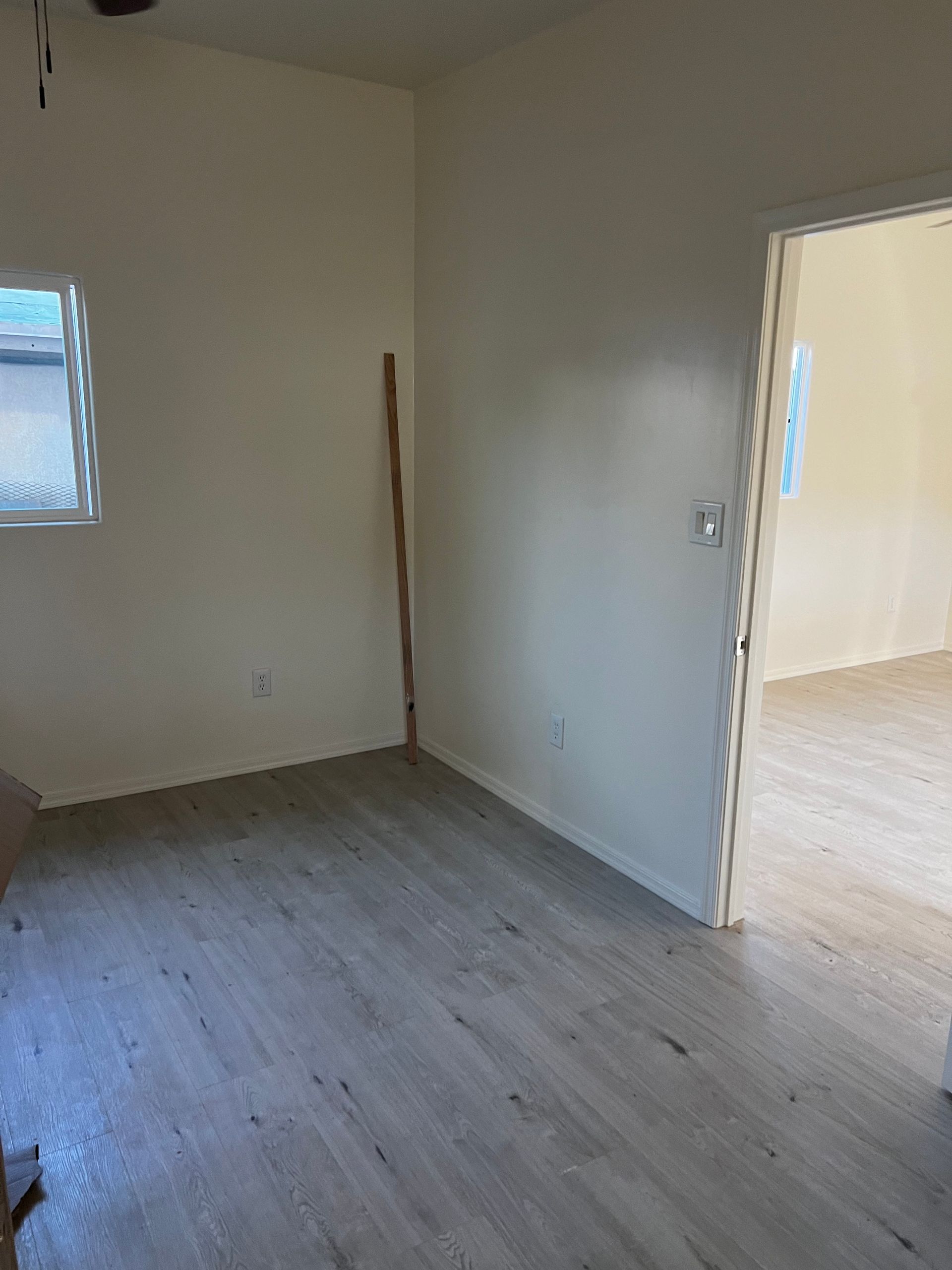 An empty room with a wooden floor and a window.