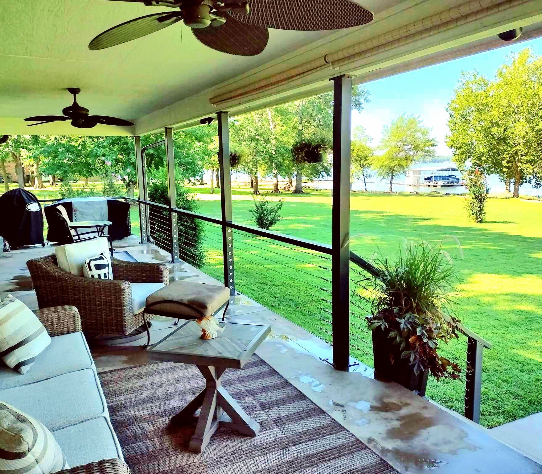 Covered porch with seating, overlooking green lawn and waterfront view.