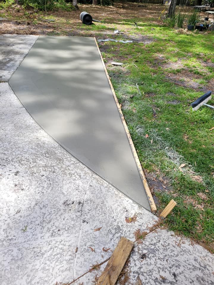 Concrete walkway pour on a driveway, bordered by grass and wood forms.