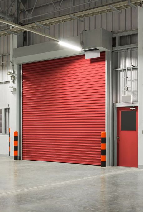 An empty warehouse with a red garage door and a red door.