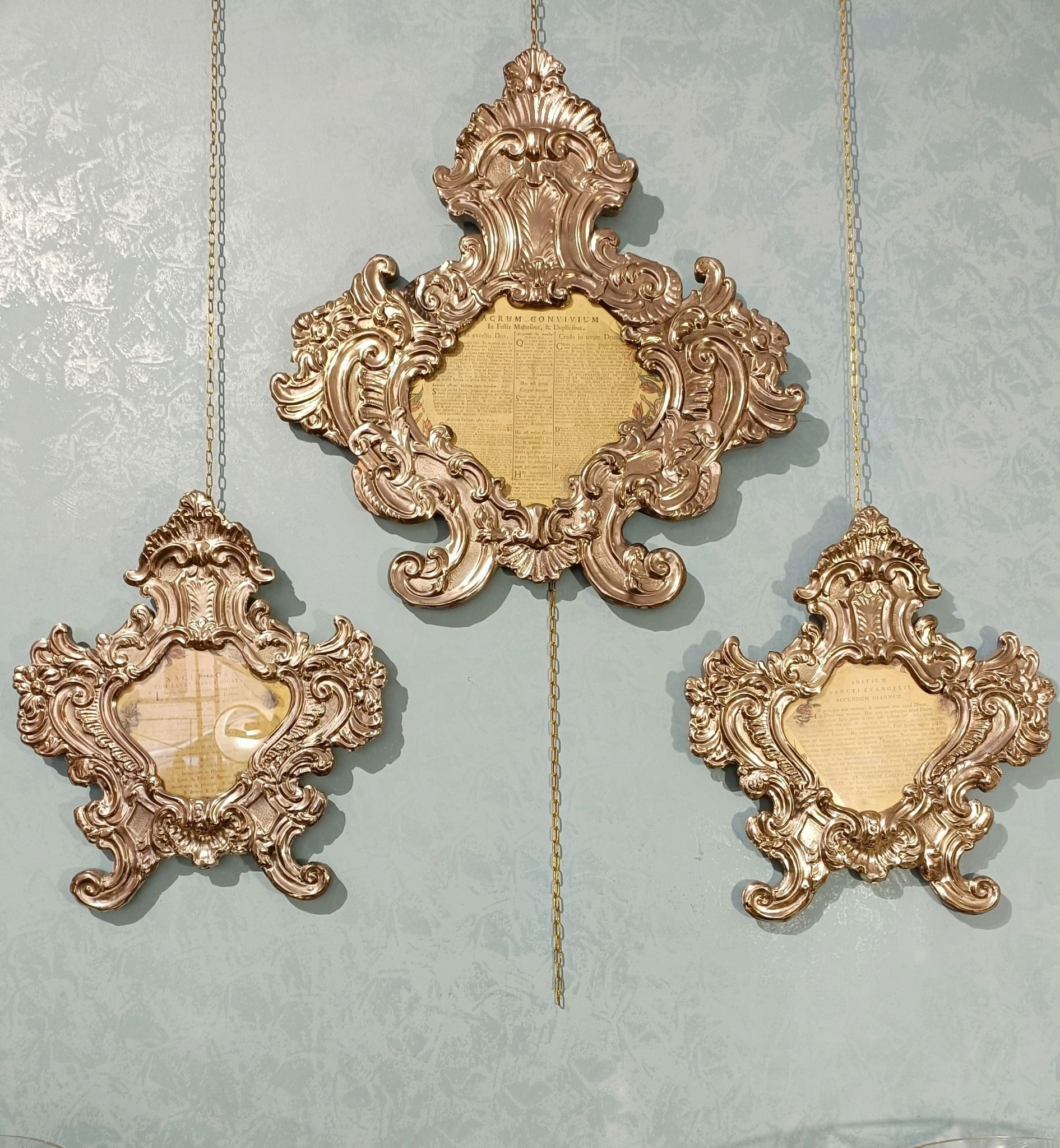 Tre cornici dorate appese a catene su un muro