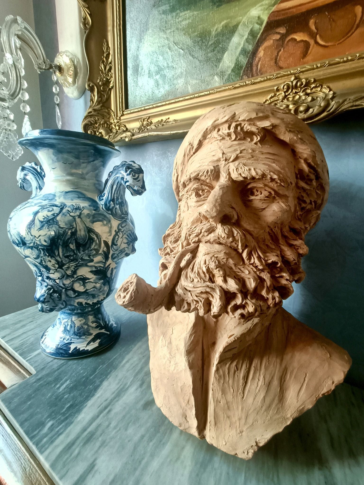 Una statua di un uomo con la barba è seduta su un tavolo accanto a un vaso.