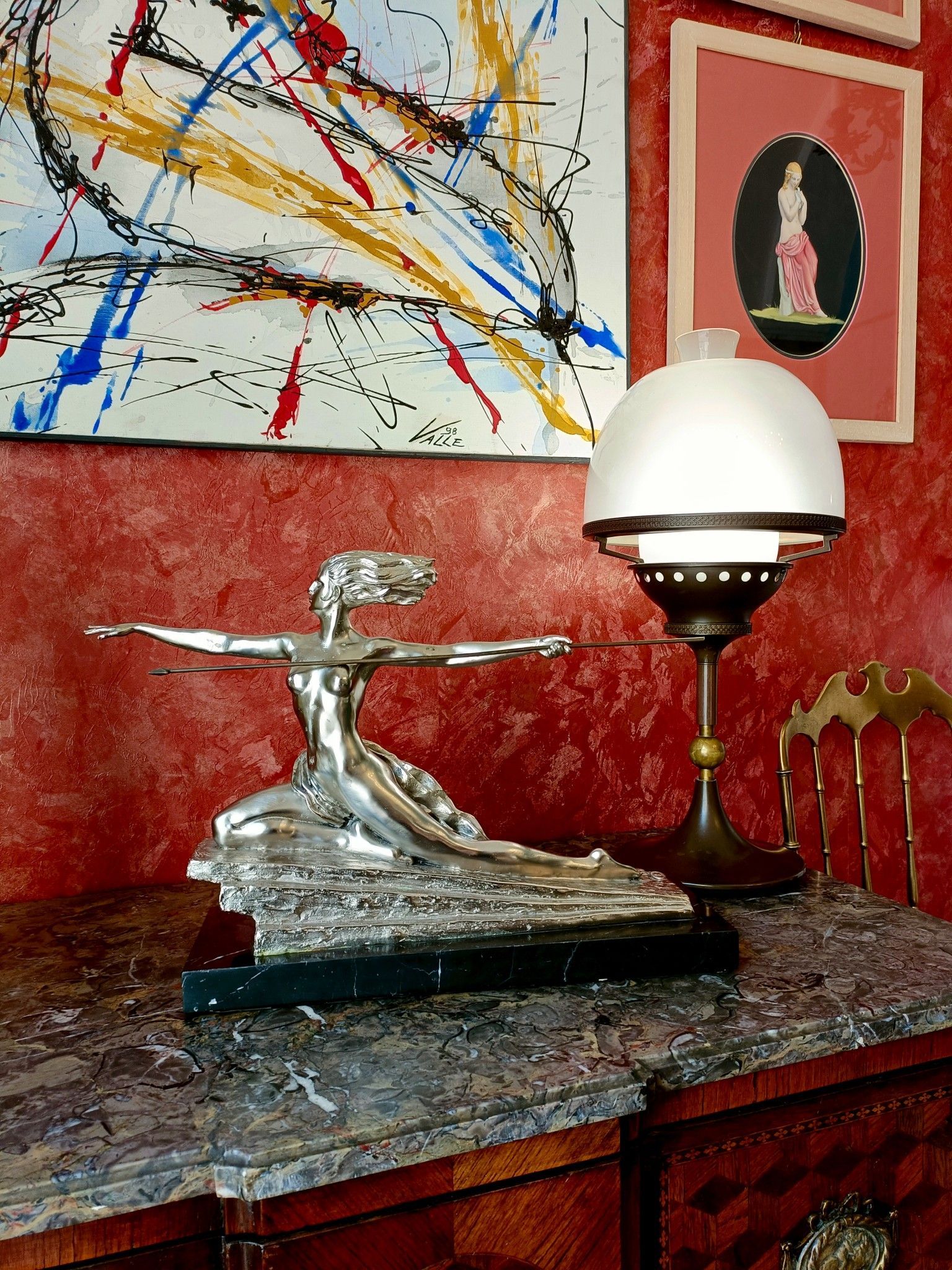 Una statua di una donna è su un tavolo accanto a una lampada