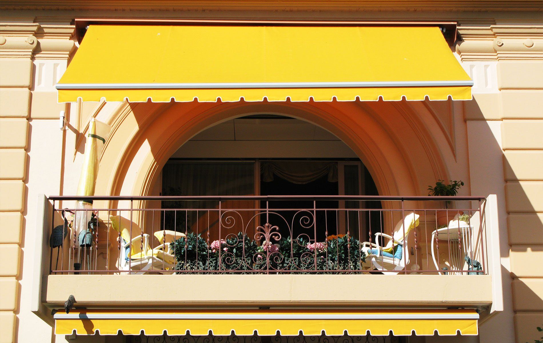 un balcone con due poltrone e una tenda da sole di color giallo