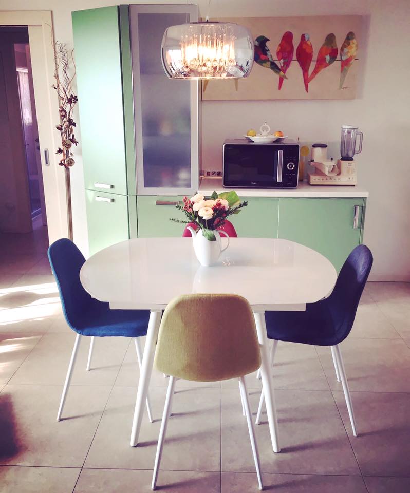 un mobile da cucina di color verde e un tavolo con sedie multicolori