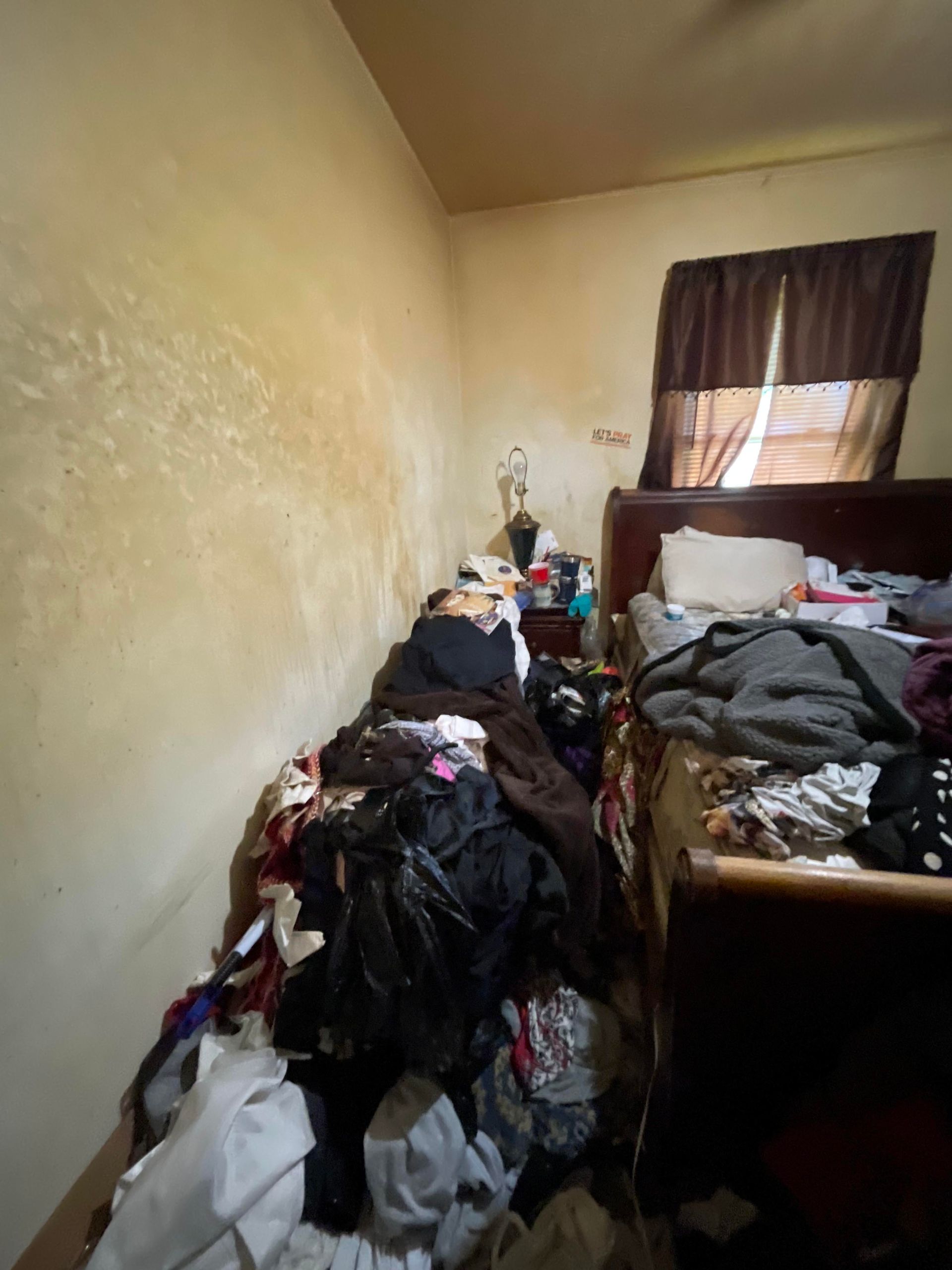 A bedroom with a bed and a lot of clothes on it