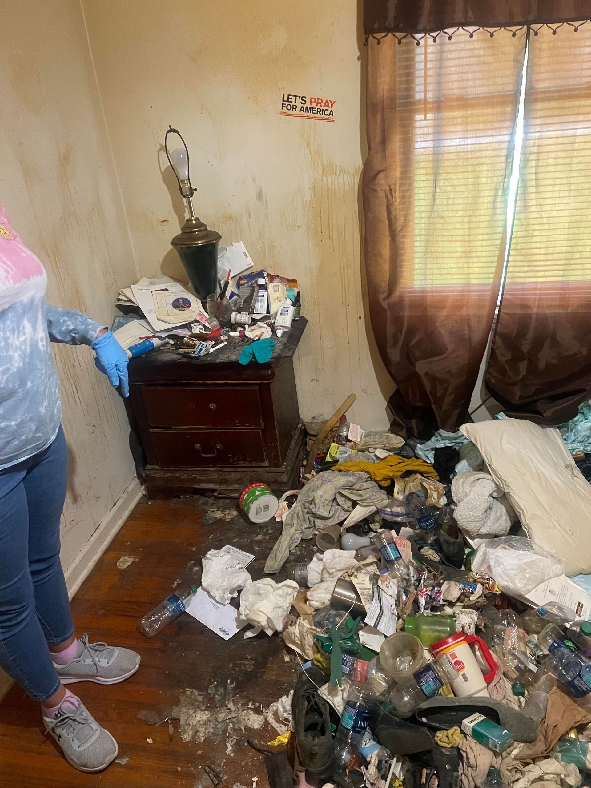 A woman is standing in a room filled with trash.