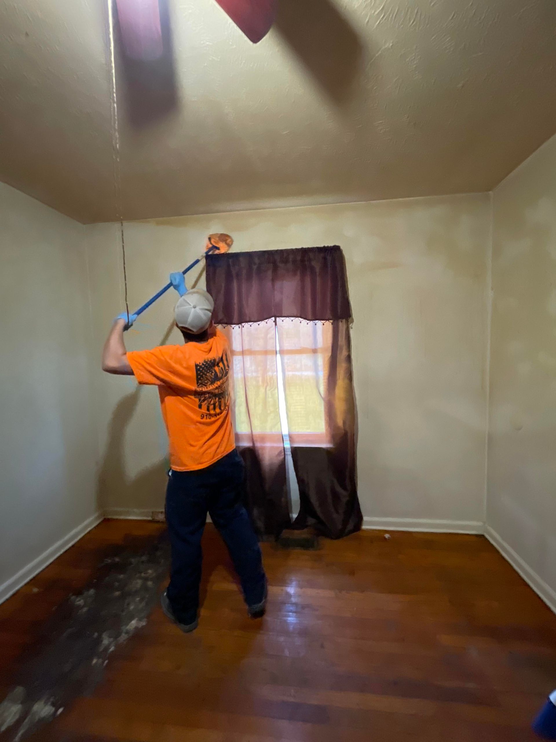 A man is cleaning a room with a mop.
