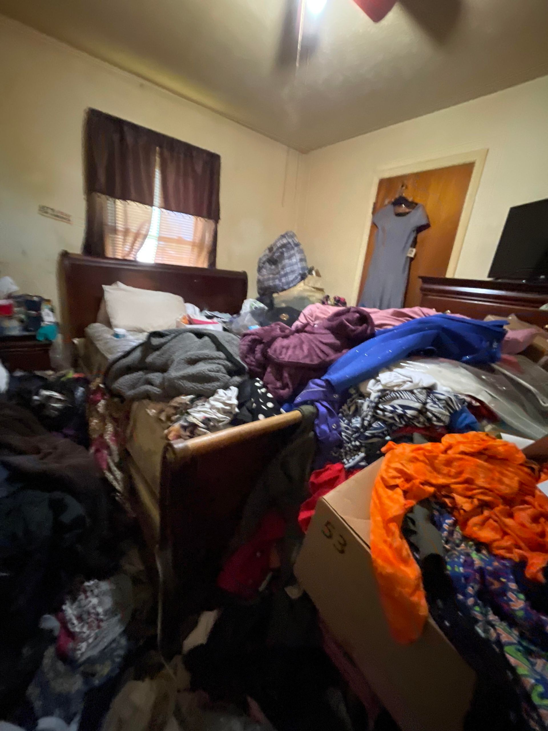A bedroom filled with lots of clothes and a bed.