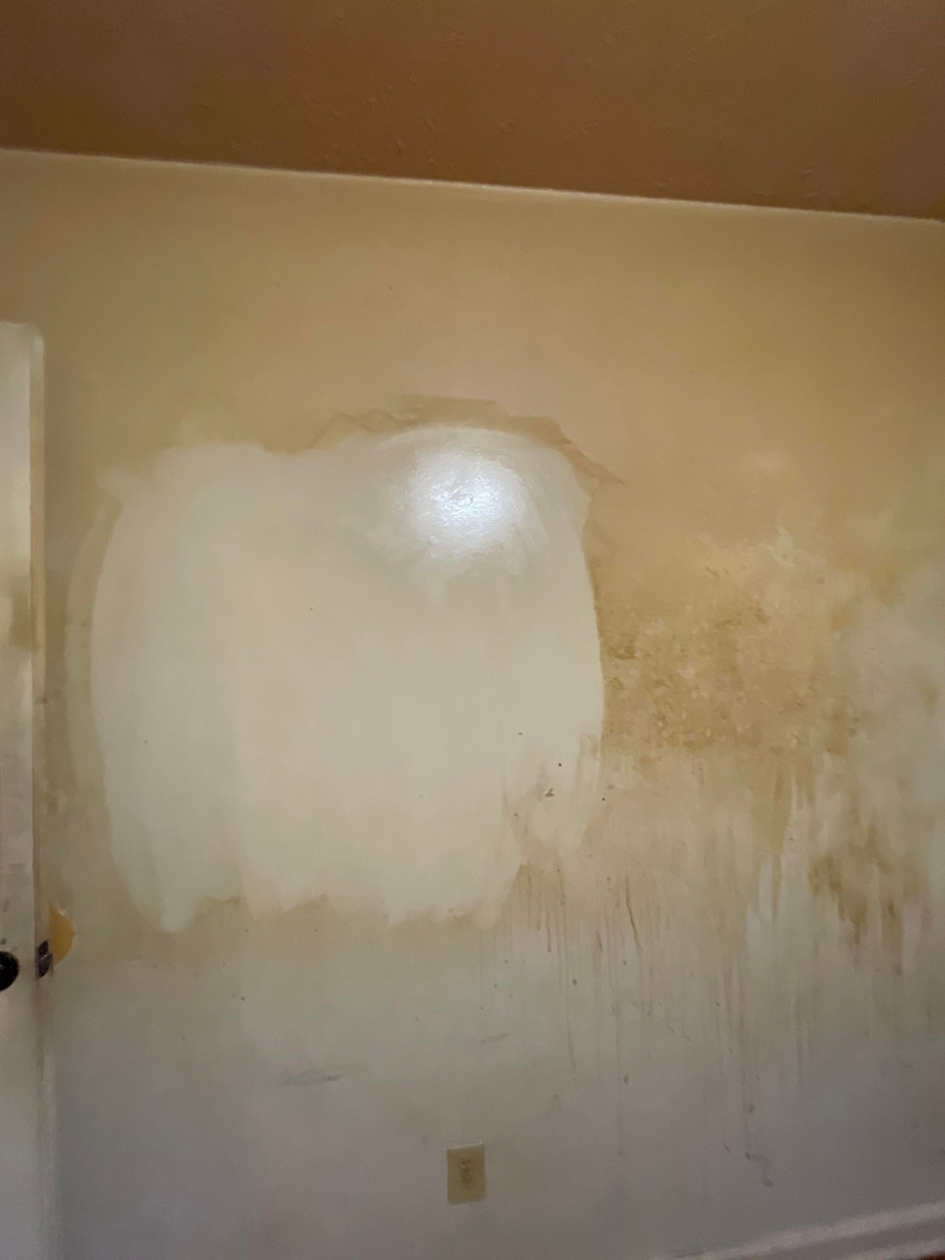 A white wall with a hole in it in a room.