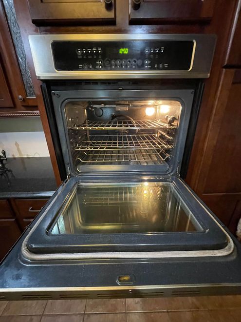 A stainless steel oven with the door open in a kitchen.