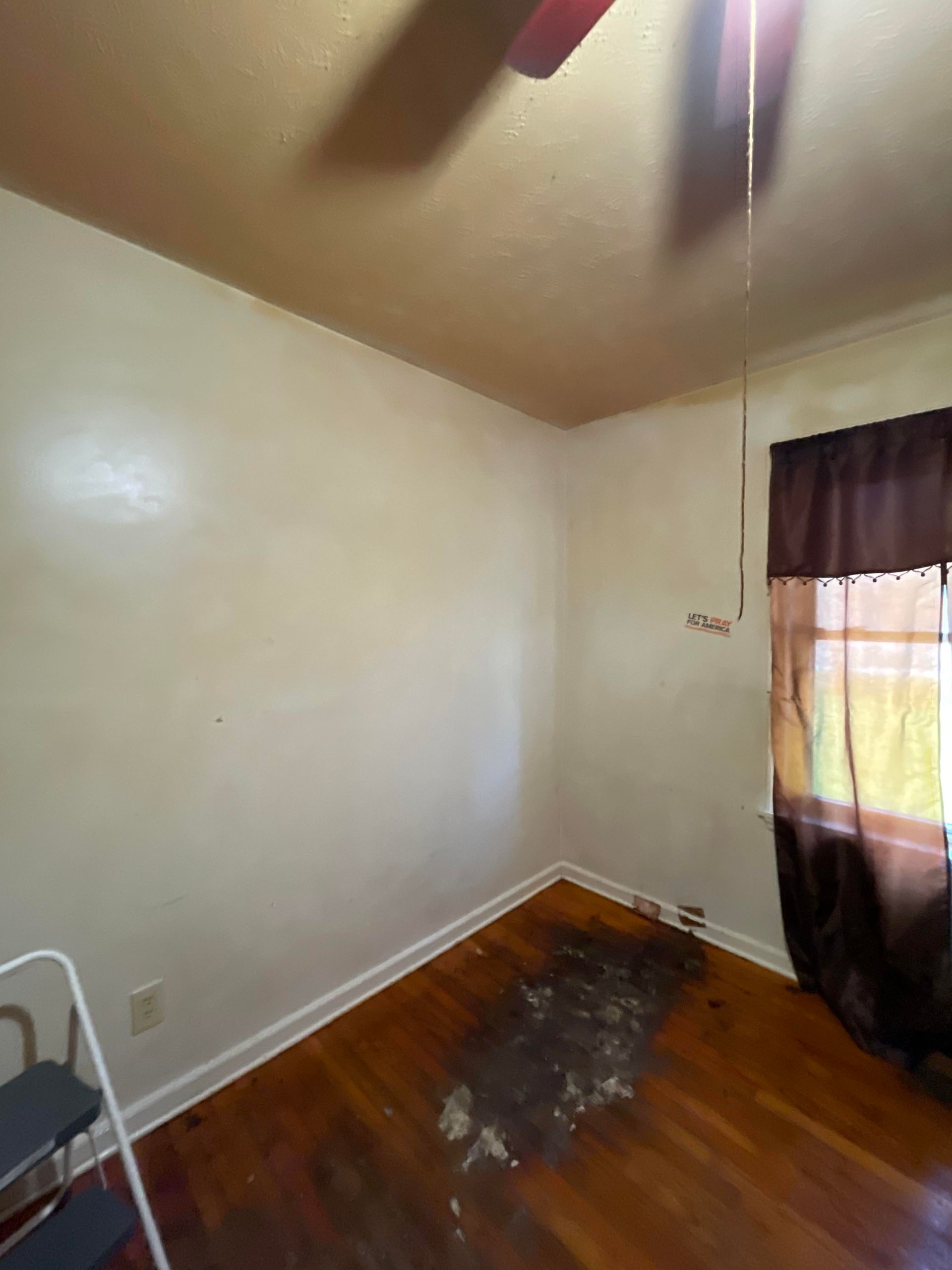 An empty room with a ceiling fan and a window