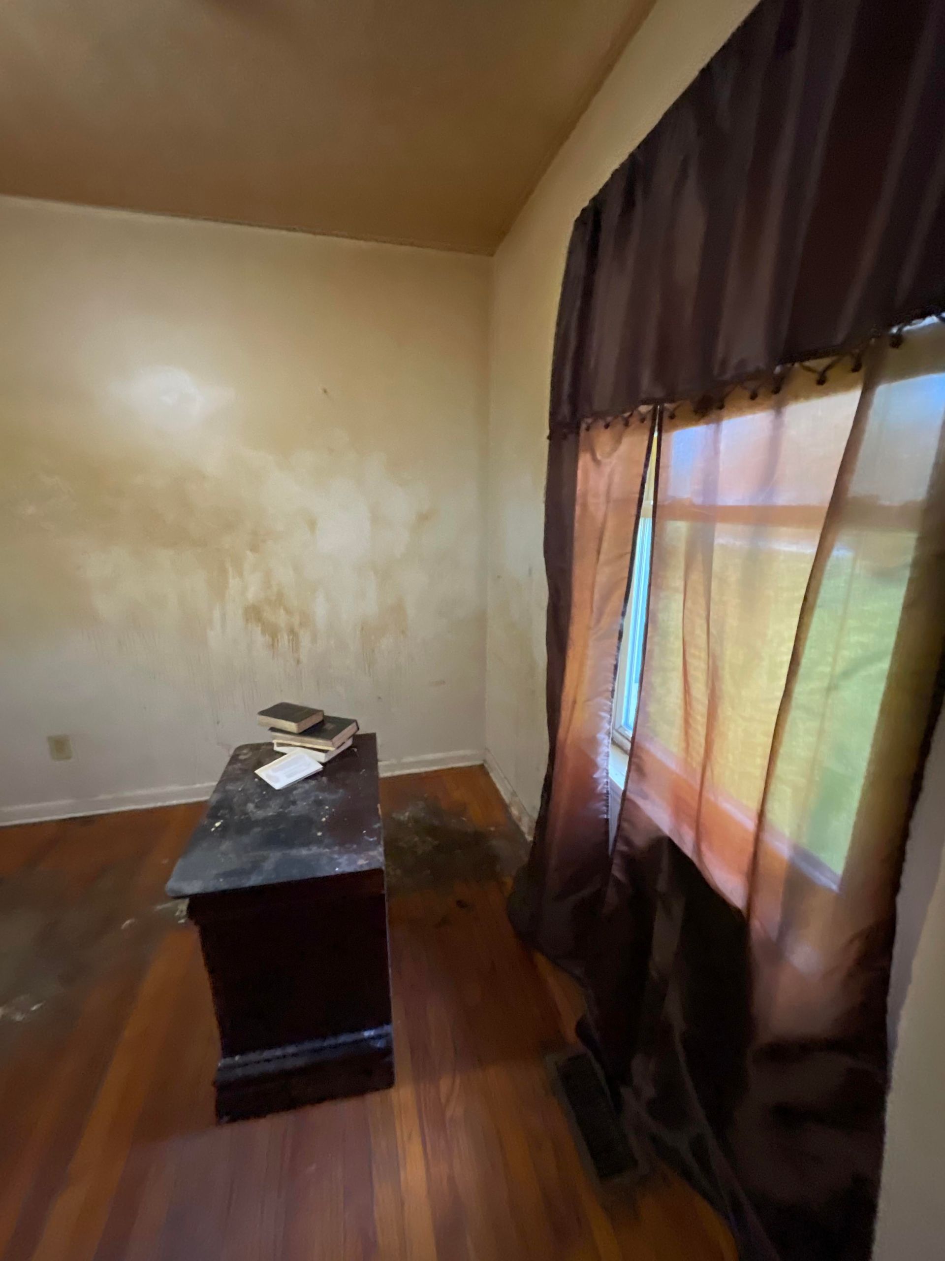 An empty room with a desk and two windows.